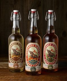 three bottles of liquid sitting on top of a wooden table