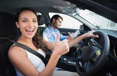 a man and woman sitting in the driver's seat of a car giving thumbs up