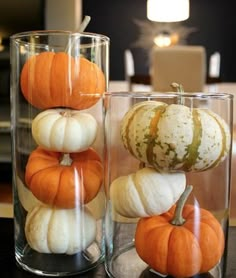 two glass vases filled with pumpkins on top of a table