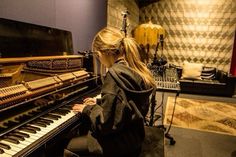 a woman sitting at a piano in a recording studio