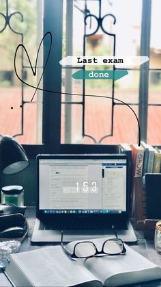 an open laptop computer sitting on top of a desk next to a book and glasses