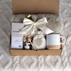 a gift box with coffee, cookies and other items in it on a white blanket