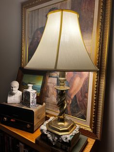 a lamp sitting on top of a wooden table next to a painting and other items