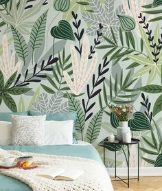 a bed sitting under a green leaf wallpaper next to a table with fruit on it