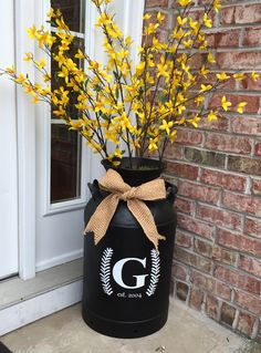 a large black container with yellow flowers in it and a bow on the front door