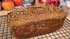 a loaf of bread sitting on top of a cooling rack next to apples and flowers