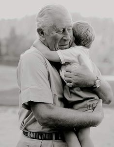 an older man holding a young boy in his arms while he is hugging him on the cheek