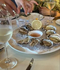 oysters and wine are served on a plate at a restaurant with people sitting around the table