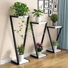 three black and white plant stands with plants on them