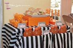 an orange and black striped table cloth is set up with bottles of juice on it