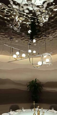 a dining room with white table cloths and lights hanging from the ceiling above it