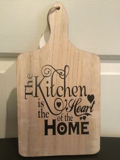 a cutting board with the words kitchen is the heart of the home on it