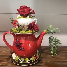 a red tea pot with flowers and a butterfly on it