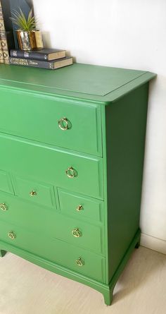 a green chest of drawers with books on top