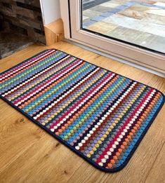 a multicolored rug sitting on the floor next to a glass door in front of a window