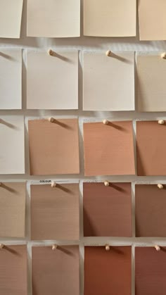 several swatches of different shades of paint on a white wall with pins in them