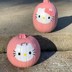 two pumpkins with hello kitty faces painted on them