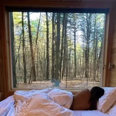 a woman is laying in bed looking out the window