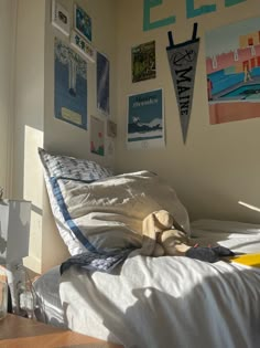 an unmade bed in a bedroom with posters on the wall and pictures above it