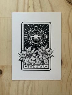 the star tarot card with three flowers on it, sitting on top of a wooden table