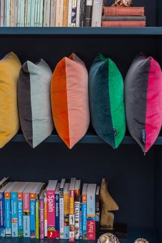 the bookshelf is filled with colorful pillows on it's sides, along with other books