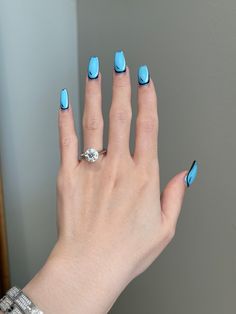 a woman's hand with blue and white nail polish holding a ring on her finger