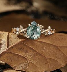 a green ring sitting on top of a leaf with diamonds in the middle and leaves surrounding it