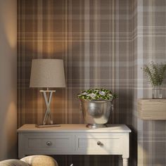 a small table with a lamp on it next to a chair and wallpapered walls