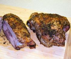 two pieces of meat sitting on top of a wooden cutting board