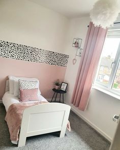 a bedroom with pink and white walls, carpeted flooring and a bed in front of a window