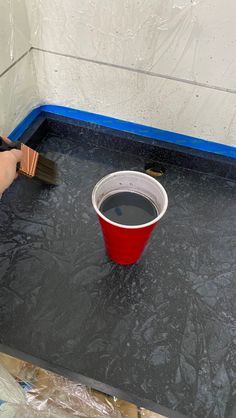 a person with a paintbrush painting a bucket on the floor in an empty room