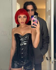 a man taking a selfie with a woman in a corset and latex