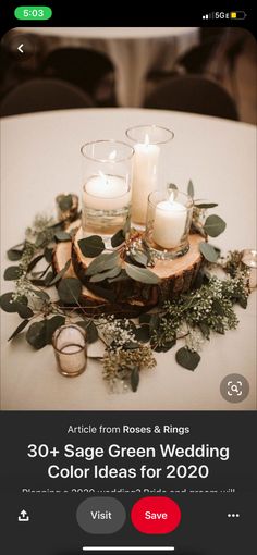 two candles are sitting on top of a wooden slice with greenery and eucalyptus leaves