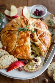 an apple pie is cut in half on a platter with bread and other fruit