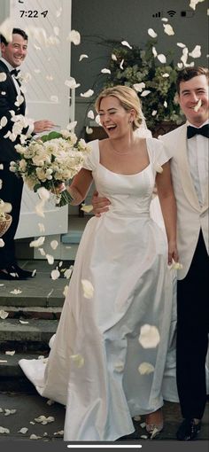 a bride and groom are walking down the steps with petals in the air as they exit their wedding ceremony