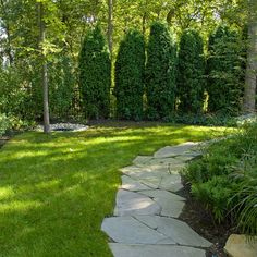 a stone path in the middle of a lush green yard