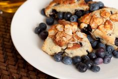 some blueberries and almonds are on a white plate next to a glass of beer