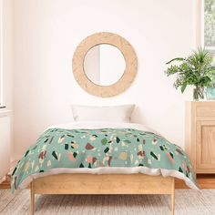 a bed in a bedroom with a round mirror on the wall above it and a plant next to it