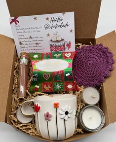 a gift box with candles, teacup and other items in it on a table