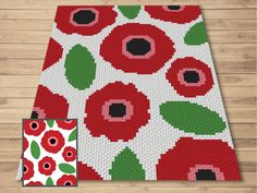 a red and green rug with flowers on it next to a piece of wood flooring