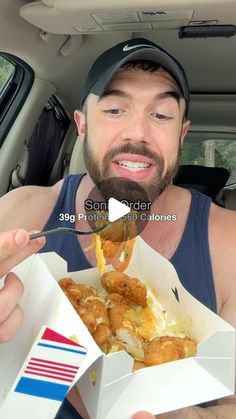 a man eating food from a box in the back seat of a car while driving