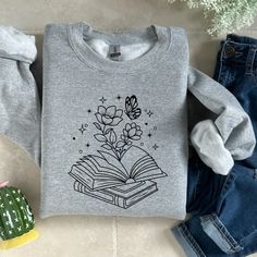 This Floral Book Sweatshirt is sure to be your favorite go-to for days with a creative flair! This super soft, lightweight sweatshirt has a unique floral book print that is perfect for a fun, whimsical look that will show off your style and personality. So don't let your inner bookworm be held back - flaunt it with pride! -Please see size chart before placing your order, to determine the best size for you.-Body Width- Measure from side seam to side seam right below sleeves-Body Length- Measure f Bookish Long Sleeve Relaxed Fit Sweatshirt, Bookish Long Sleeve Cotton Tops, Casual Cotton Sweatshirt With Printing, Casual Cotton Printed Sweatshirt, Bookish Cotton Sweatshirt With Letter Print, Spring Graphic Print School Sweatshirt, Cotton Letter Print Bookish Sweatshirt, Spring Graphic Print Sweatshirt For School, Graphic Print Sweatshirt For School In Spring