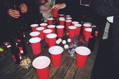 several people standing around red cups on a table