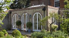 an old brick building with white doors and windows on the outside, surrounded by greenery