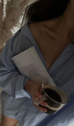 a woman holding a glass of wine and an open book