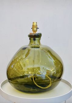 a green glass bottle sitting on top of a white table next to a yellow cord