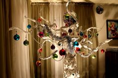 a christmas tree with ornaments hanging from it's branches in front of a window