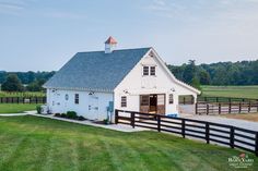 a large white barn with a black fence around it