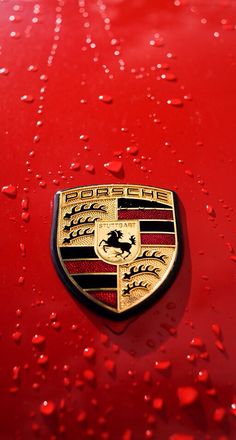 the front end of a red car with water droplets on it and a black ferrari logo