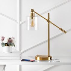 a table lamp on a white shelf next to a potted plant